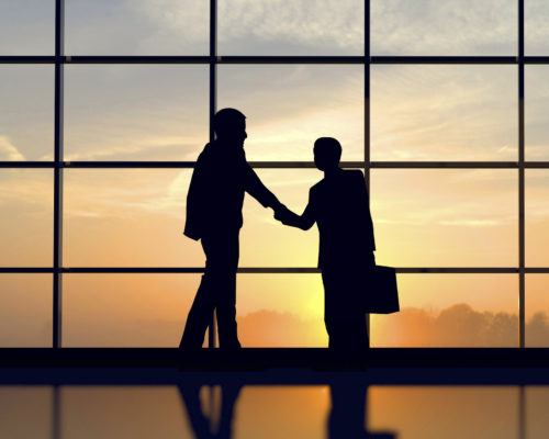 Two business people shake hands against sunset Two business people shake hands against sunset